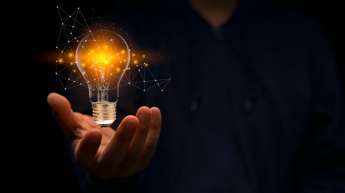Image shows a hand holding a lightbulb surround by darkness